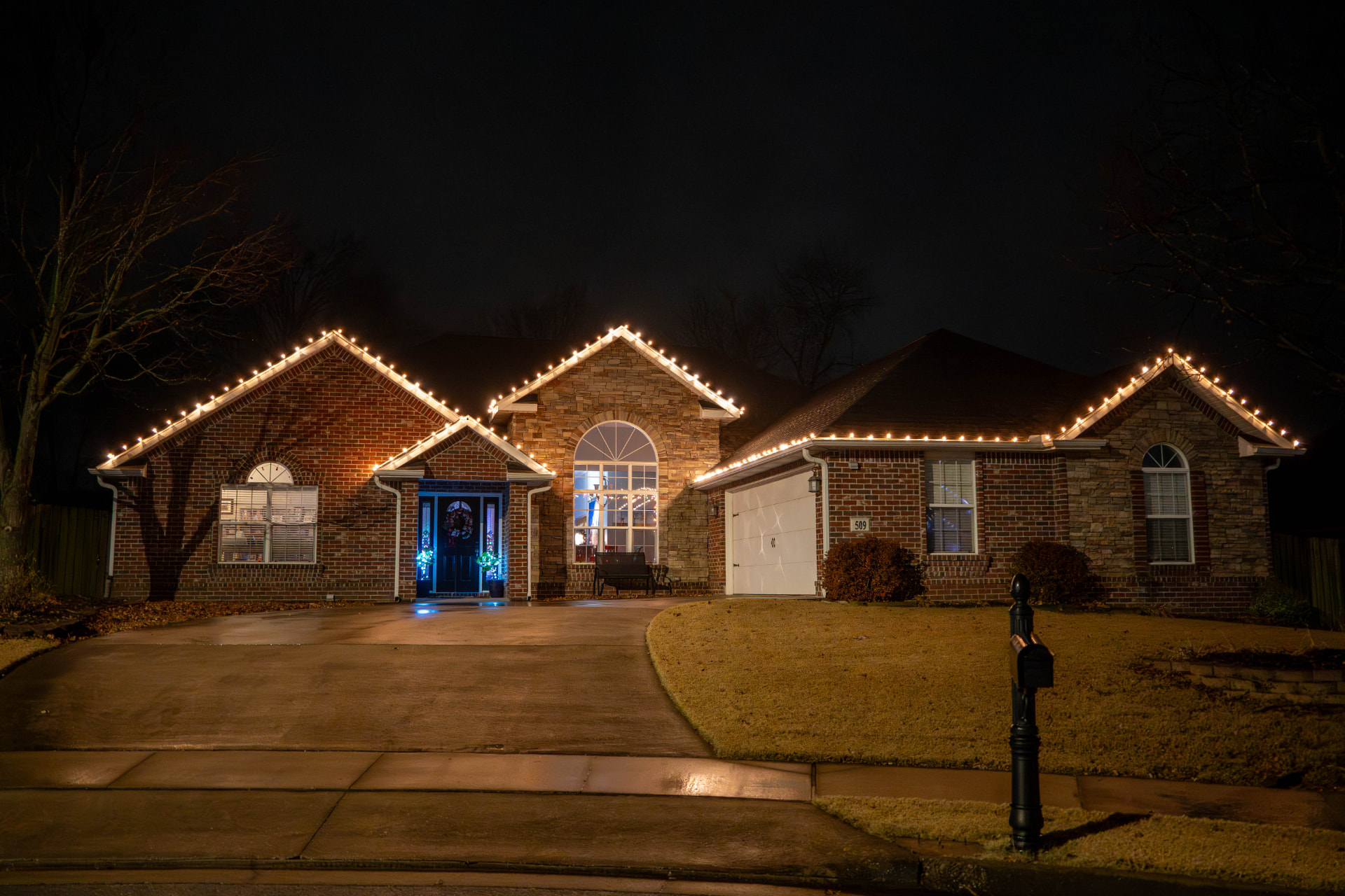 Brick and stone home outlined in warm white holiday lights