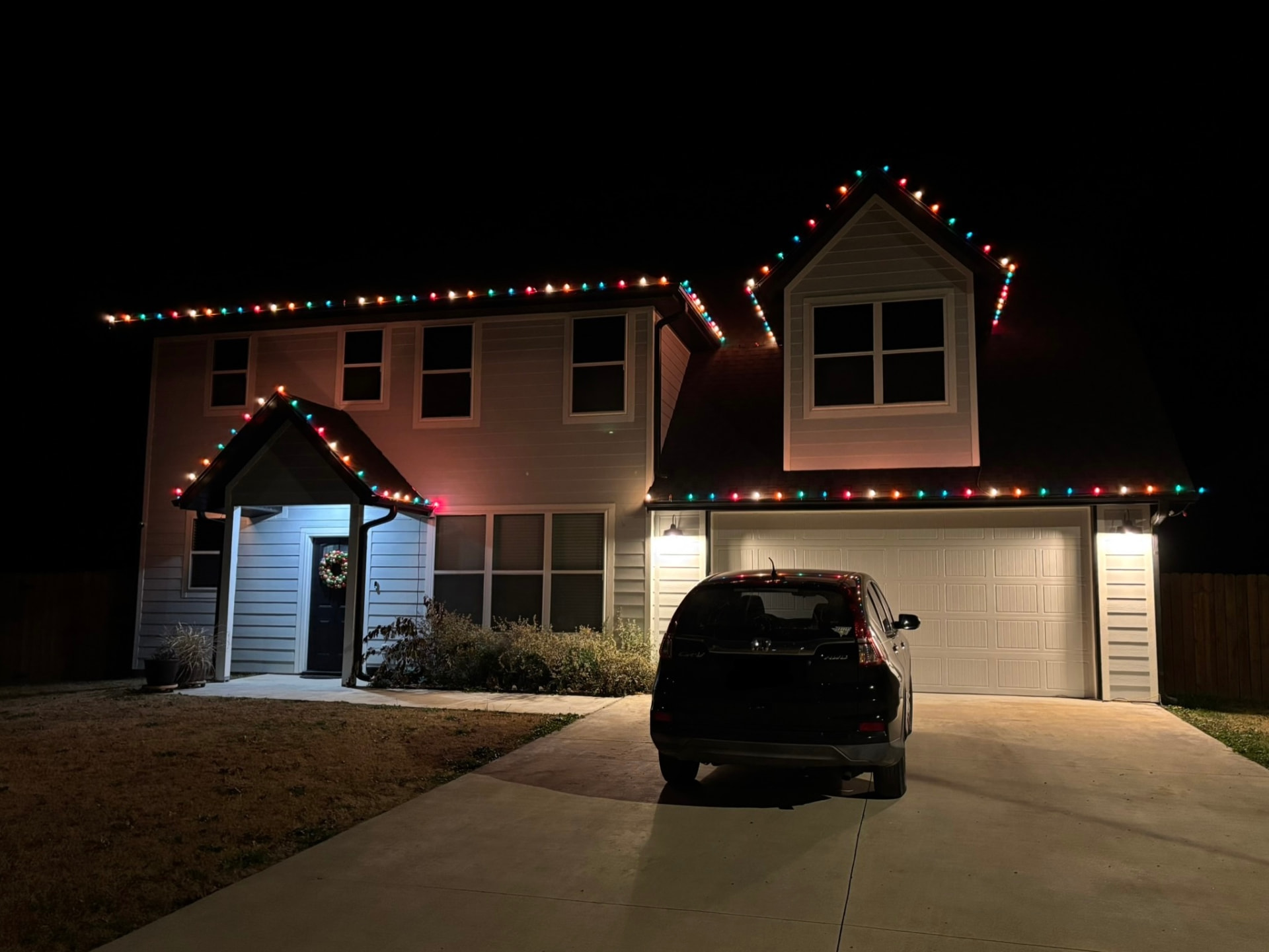 Two-story home outlined in multicolor holiday lights